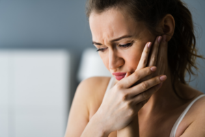 Women holding cheek due to tooth decay pain